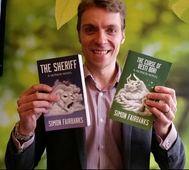 Author Simon Fairbanks holding up two books: The Sheriff and The Curse of Besti Bori.